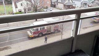 Naked on balcony with fire trucks in background